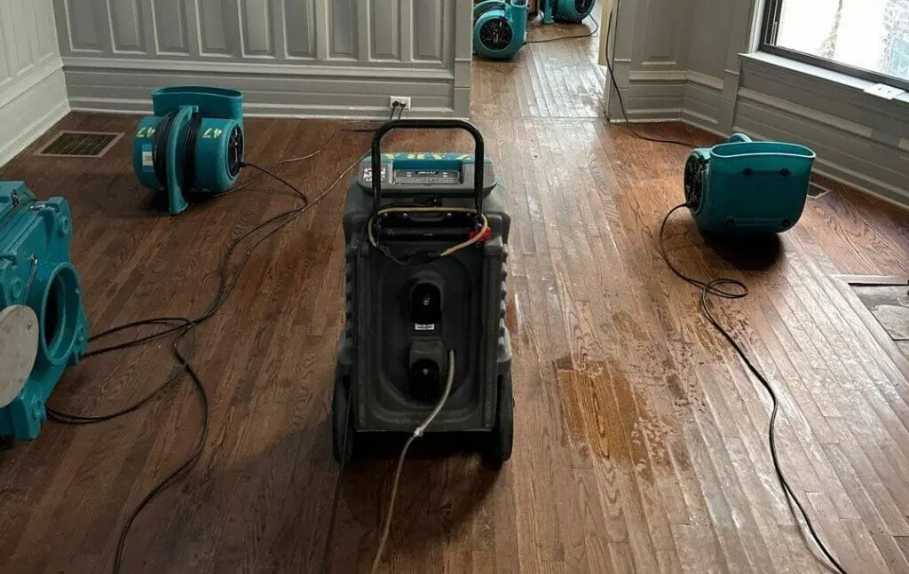 Dehumidifier and air movers drying a wet hardwood floor after water removal