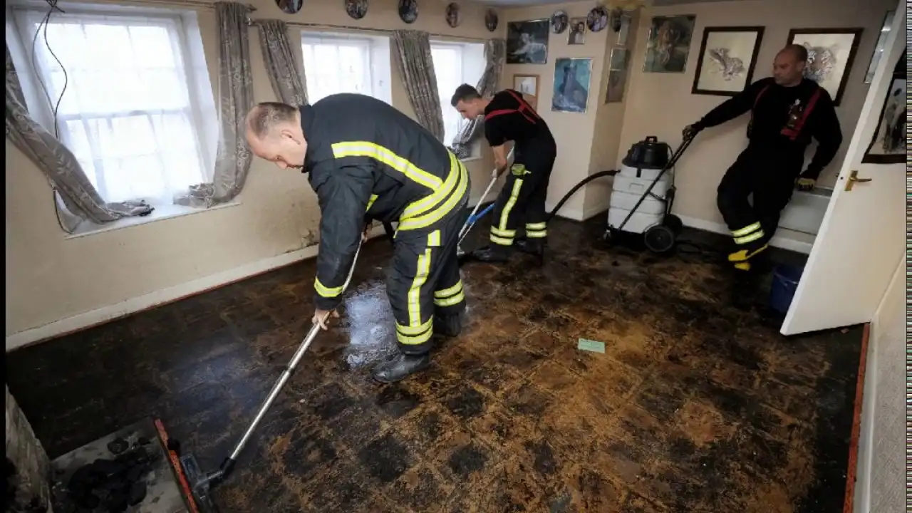 Crew vacuuming soot and firefighting water off a burned living room floor
