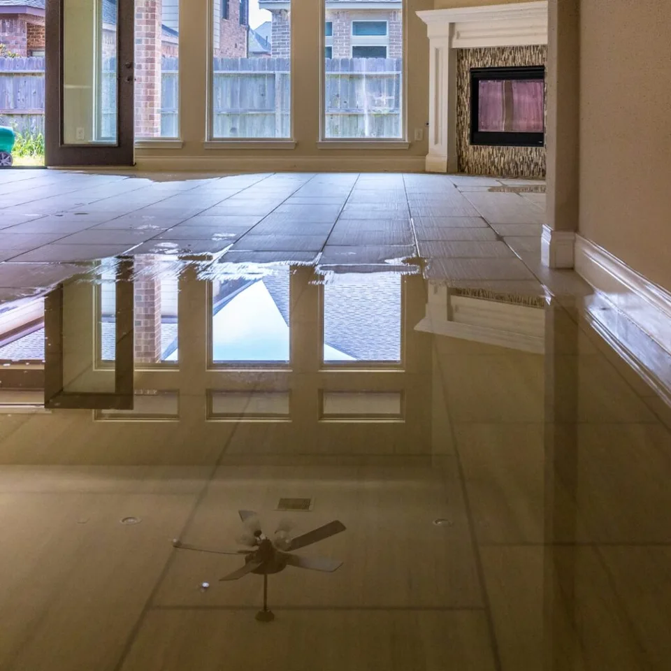 Flood water standing across the tile floor of a living room after a storm
