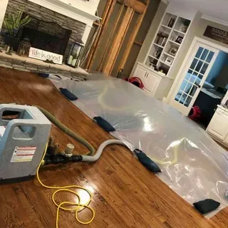 Drying mats and a drying unit set up on a wet hardwood floor in a living room