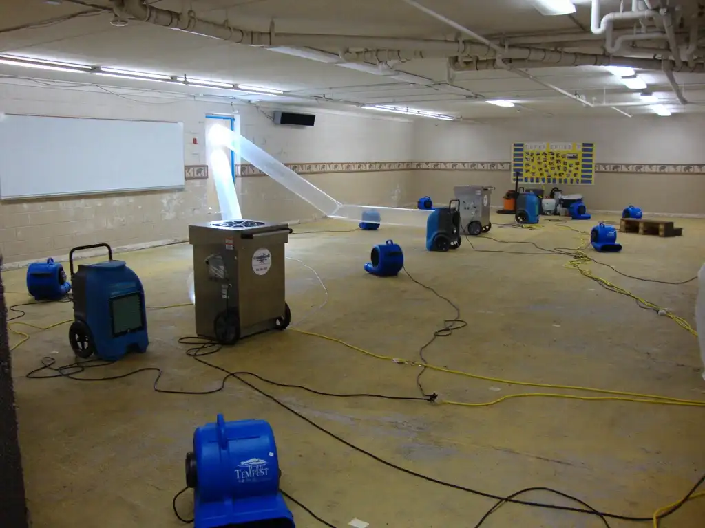 Air movers and dehumidifiers drying a water-damaged room